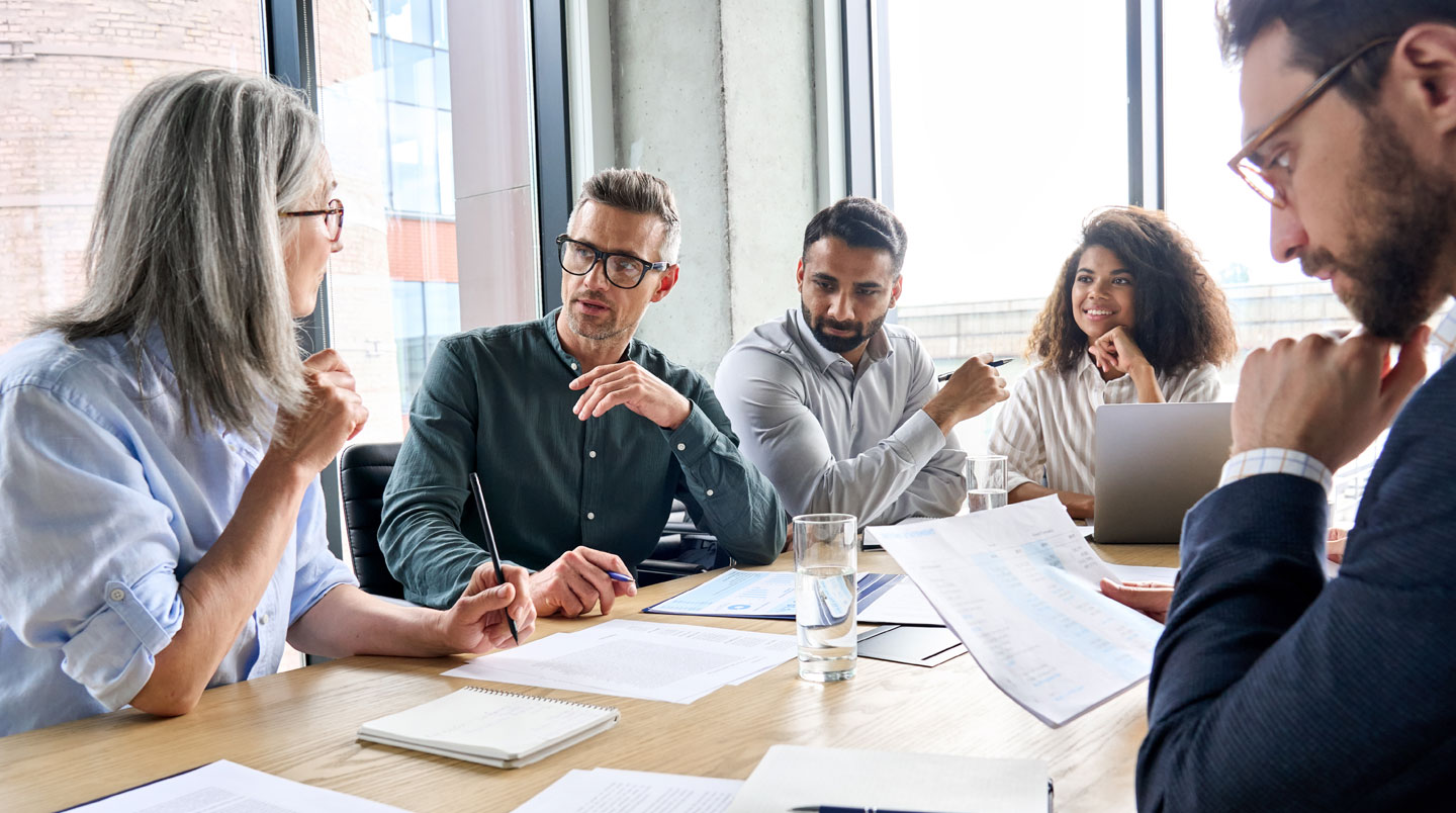 Une salle de formation vide avec table ronde, paperboards et grandes fenêtres laissant entrer la lumière naturelle